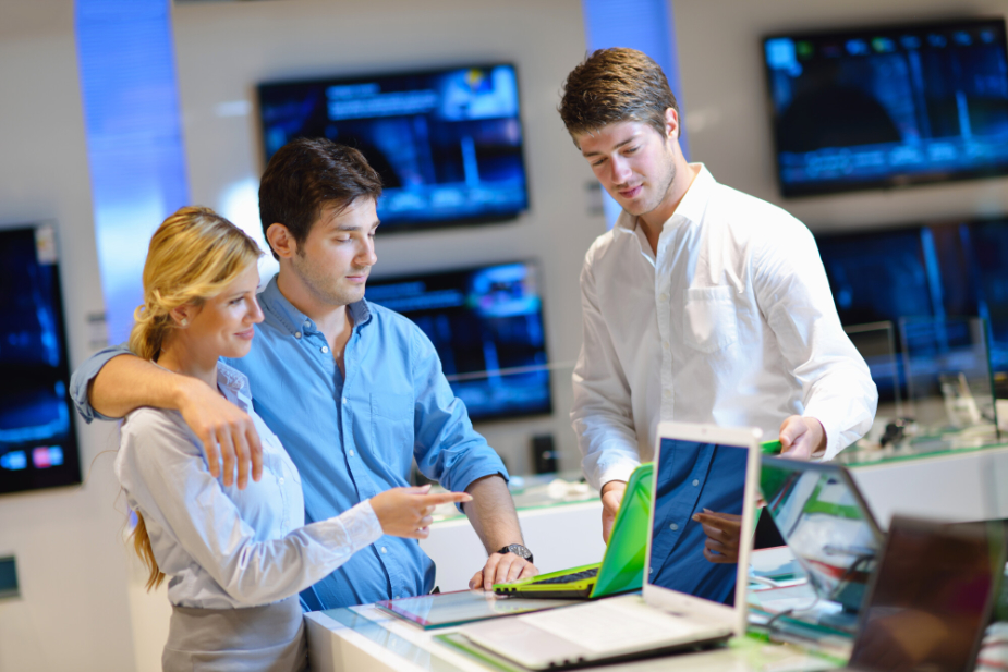 salesman showing laptops to a couple